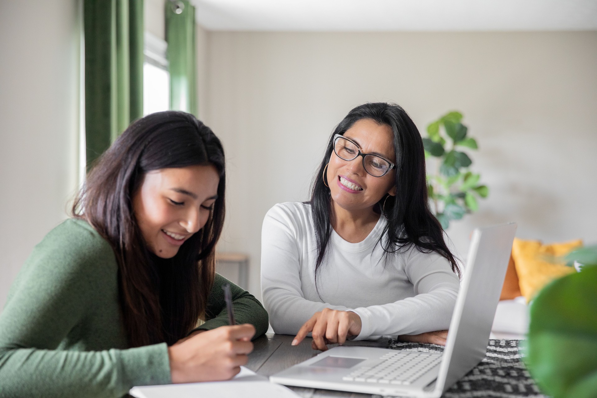 With a home laptop, a mother guides her teenage daughter through a virtual high school project.